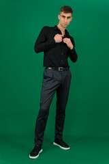 a man in black on a green background Young happy smiling IT man isolated on plain green background studio portrait. Lifestyle concept. High quality photo