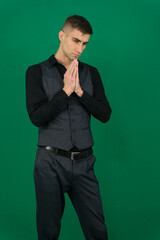 Young Latino man posing on yellow background holding hands in pray near mouth, feels confident. High quality photo