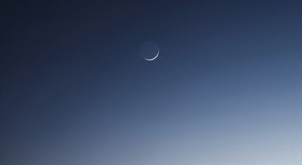 A thin crescent moon is visible in the deep blue twilight sky, with a gradient of lighter blue towards the horizon.