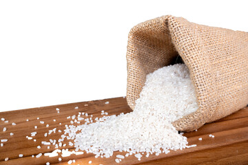 rice spills scattered from a burlap sack onto a wooden tray with a white isolated background