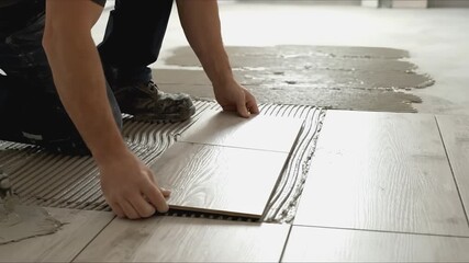 Skilled worker applying adhesive to floor tiles, showcasing the meticulous process of tile installation with a focus on craftsmanship and precision