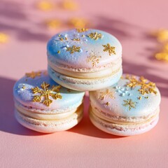 Three pastel macarons with golden snowflakes on a pink surface