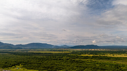 Expansive landscape with lush greenery in foreground rolling hills midground distant mountains under partly cloudy sky