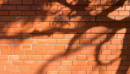 Close-up of a red brick wall with shadows cast by foliage. The texture is rough with visible mortar lines