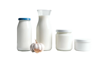 Assortment of dairy products milk in bottles, yogurt in jars, and a clove of garlic arranged against a black background