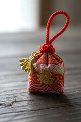 Close-up of a traditional Japanese New Year charm with hieroglyph "Luck" resting on a wooden surface, captured in soft light for a peaceful seasonal mood.