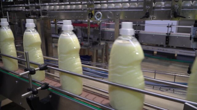 Bottles of fabric softener moving along a conveyor belt. 
Liquid detergent on production line.  Industrial production line of soap products at a modern detergent production plant. 
