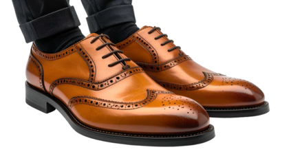 Close-up of stylish brown leather brogue shoes with intricate details, black laces, and visible dark pants