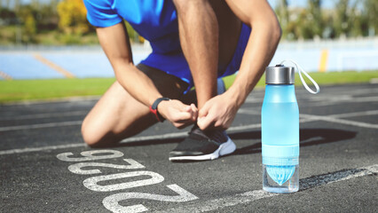 New Year. Man Tying Shoelaces near Numbers 2026 on Road at Stadium, Closeup
