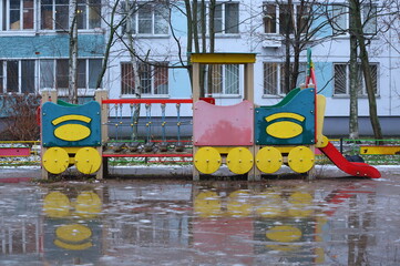 A toy wooden steam locomotive on a playground in the courtyard of a residential building on a warm winter day, Bolshevik Avenue, Saint Petersburg, Russia, December 25, 2025