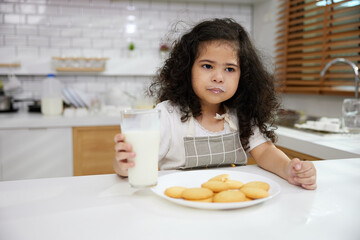portrait child girl drinking fresh milk and enjoy eating cookies in the kitchen