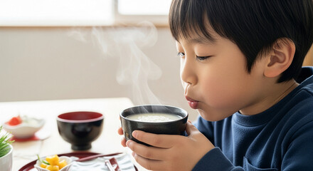 熱い甘酒に息を吹いて冷ます日本の男の子、お正月の日常とコピースペース