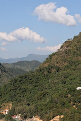 Panoramic autumn mountain landscape featuring a high peak view over a misty forest valley with green trees and a lake under a cloudy sky in Laos