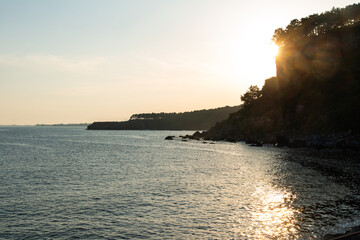 idyllic seascape with cliff and shore during sunset
