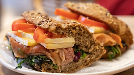 appetizing whole grain bread sandwich with brie cheese, prosciutto ham and tomatoes