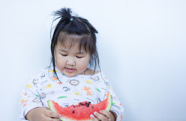 A cute little Asian girl is happily eating watermelon,lovely little asian girl eating watermelon on white background,cute little asian girl in chinese traditional dress and eating watermelon on white 