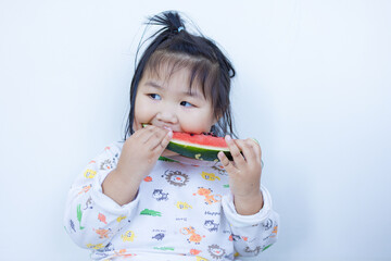 A cute little Asian girl is happily eating watermelon,lovely little asian girl eating watermelon on white background,cute little asian girl in chinese traditional dress and eating watermelon on white 