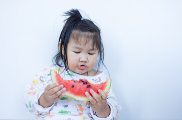 A cute little Asian girl is happily eating watermelon,lovely little asian girl eating watermelon on white background,cute little asian girl in chinese traditional dress and eating watermelon on white 