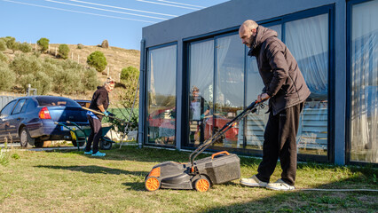 A mother and her middle-aged son working together on garden maintenance in their garden on a winter day