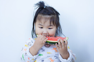 A cute little Asian girl is happily eating watermelon,lovely little asian girl eating watermelon on white background,cute little asian girl in chinese traditional dress and eating watermelon on white 