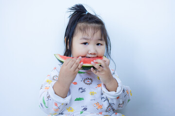 A cute little Asian girl is happily eating watermelon,lovely little asian girl eating watermelon on white background,cute little asian girl in chinese traditional dress and eating watermelon on white 