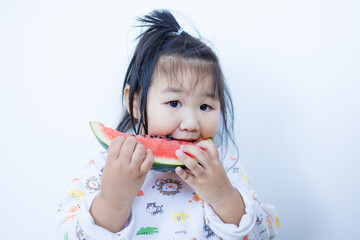 A cute little Asian girl is happily eating watermelon,lovely little asian girl eating watermelon on white background,cute little asian girl in chinese traditional dress and eating watermelon on white 
