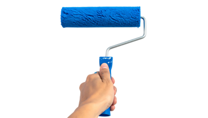 A hand holds a blue paint roller against a black background