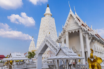 Beautiful white pagoda and chapel of Wat Bung Nam Rak temple in Thailand under blue sky,Magnificent white Thai Buddhist temple architecture featuring a large stupa (Chedi) 