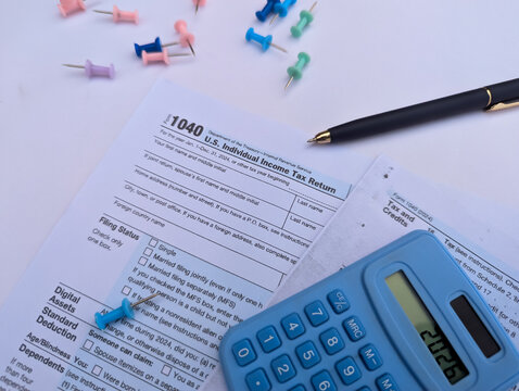 US IRS Form 1040 individual income tax return sheet with calculator showing year 2026 on white background