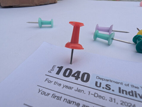 Red pushpin on IRS Form 1040 marking tax filing deadline