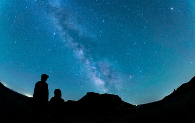 Silhouette of parent and child stargazing at the Milky Way under the starry sky at Craters of the Moon National Monument (Fisheye view) © hibaRi