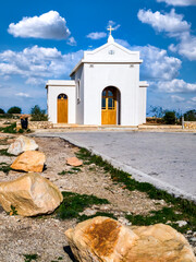 Chapel of the Immaculate Conception in Mellieha, Malta on a rocky plateau overlooking the sea under a clear blue sky.