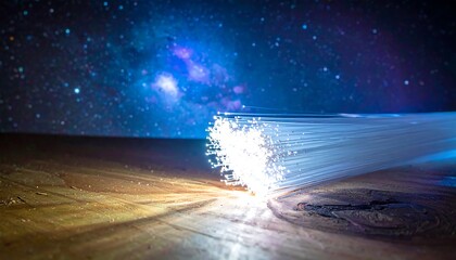 Close-up of illuminated fibers on a wooden surface, with a blurred starry background. The fibers radiate light