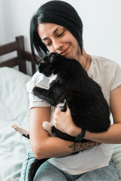 A portrait of a young woman hugging a shorthair cat at home. People and animals concept.