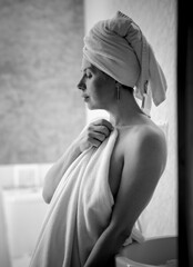 Intimate black and white lifestyle shots of a woman by a window and wrapped in a bath towel after a shower.