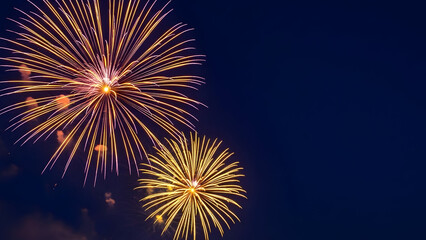 Vibrant fireworks exploding in the night sky with bright yellow and orange lights