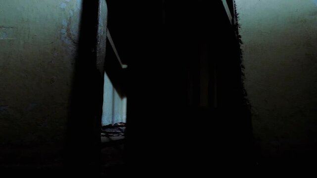An authentic old prison cell, taken outside at ground level. the door is opening and closing, showing the small cell, with a bit of a rug on the floor and the mighty shadow the door is casting.