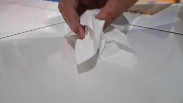 closeup of a hand picking up a cockroach on a white ceramic floor