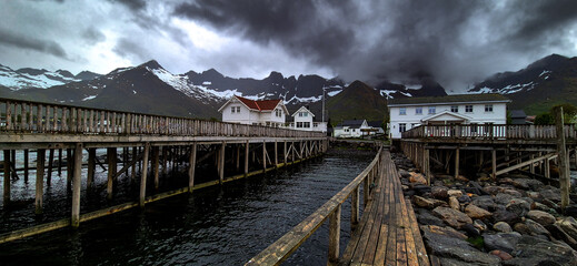 Cottages, Wooden Pier And Snowy Mountains In Mefjordvaer On Senja Island In Norway