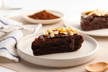 Sliced chocolate brownie cake with a topping of Cashew nuts.served on white plate.