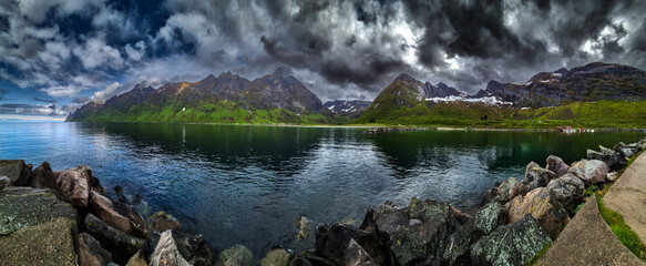 Calm Fjord With Red Huts In Front Of Snowy Mountains On Senja Island In Norway