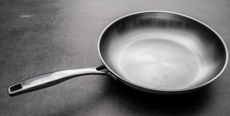Stainless steel frying pan waiting on a kitchen countertop, ready to be used for cooking, close up