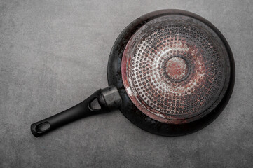 Dirty old non-stick frying pan on grey background