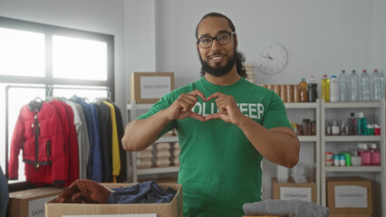 Man forms heart with hands over a donation box in a building volunteer room; community support compassion.