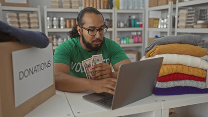 Man counting cash at donations table in community building wearing volunteer shirt and stacking...