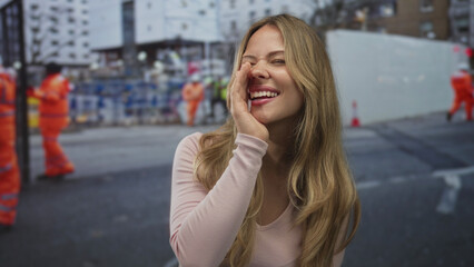 Woman with hand to mouth shouting on busy urban construction site; urgency warning alert...
