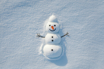 A winter scene featuring a three-tiered snow figure holding sticks and smiling. Viewed from above on a textured white surface with soft blue shadows.