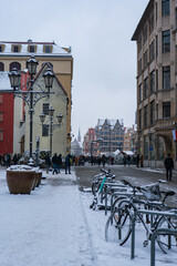 Wintry Wroclaw street with Rynek facades, bikes, lamps, and spire