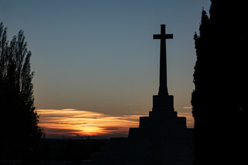 Silhouette of WWI Cross of Sacrifice at sunset in Flanders Fields Belgium. World War I military memorial monument against colorful evening sky. Remembrance and peace on the Western Front.
