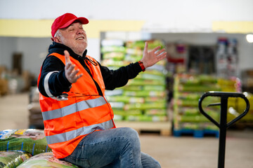 An older worker in a pet food warehouse prepares deliveries of goods for pet stores.Cheerfully does his job.